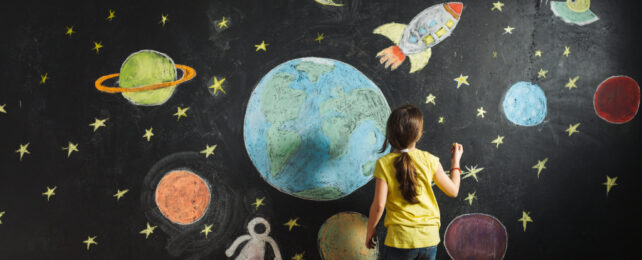 child drawing planets on a chalkboard