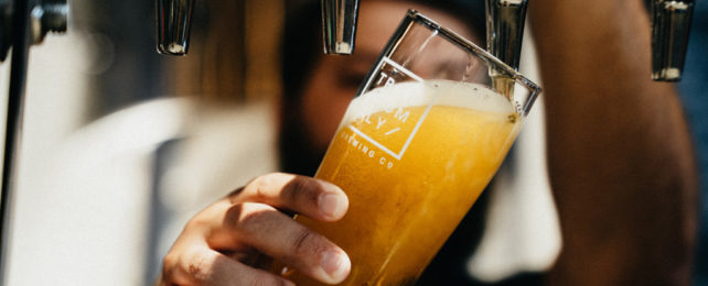 A man fills a pint glass using a beer tap.