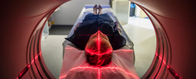 Person in dark blue scrubs lying in MRI machine, head in foreground of the image.