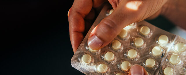 fingers pressing a pill out of a blister pack